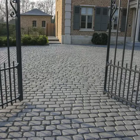 Gilaus tamsiai pilko atspalvio akmens imitacijos betoninių trinkelių kiemo grindinys už vartų